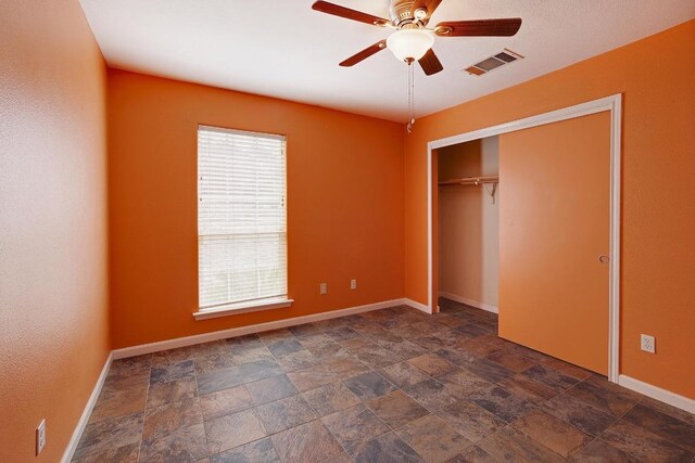 4142 Rockwood Dr, Lago Vista, TX 78645 - unfurnished bedroom featuring stone finish flooring, a closet, and a ceiling fan