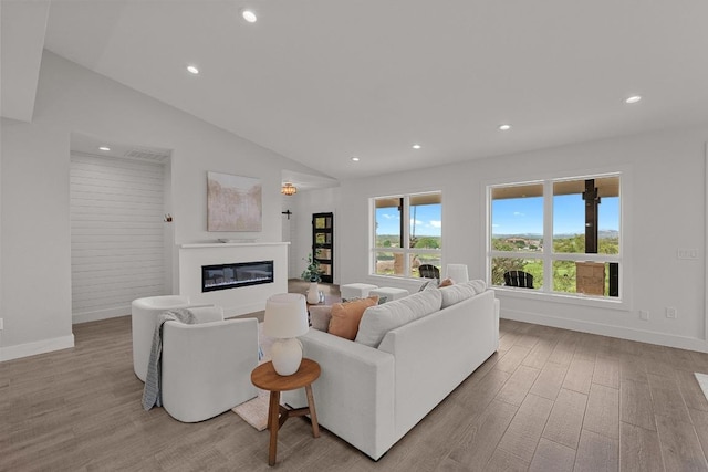 509 Flamingo Blvd, Lakeway, TX 78734 - living room featuring wood finished floors, a glass covered fireplace, recessed lighting, lofted ceiling, and baseboards