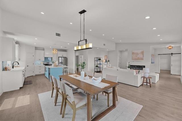 509 Flamingo Blvd, Lakeway, TX 78734 - dining area with recessed lighting, light wood finished floors, a barn door, and a glass covered fireplace