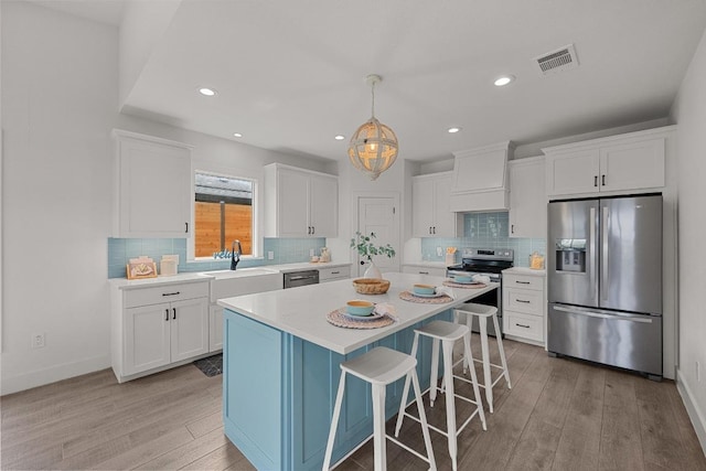 509 Flamingo Blvd, Lakeway, TX 78734 - kitchen featuring stainless steel appliances, custom range hood, light wood-style floors, white cabinets, and recessed lighting