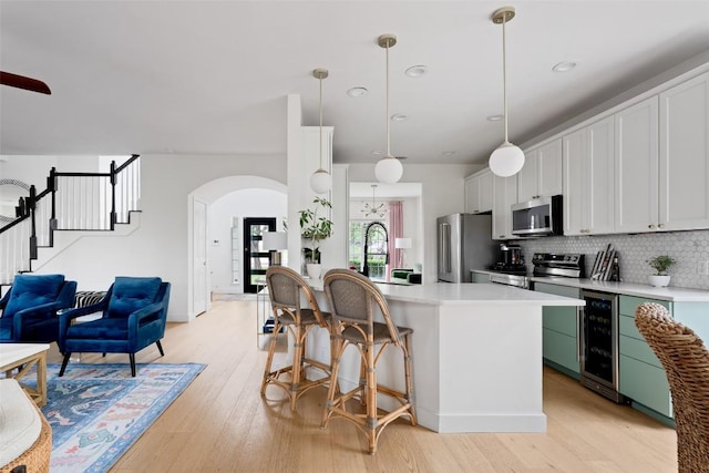 102 Hurst Creek Rd, Lakeway, TX 78734 - kitchen featuring appliances with stainless steel finishes, beverage cooler, arched walkways, light wood-style flooring, and recessed lighting