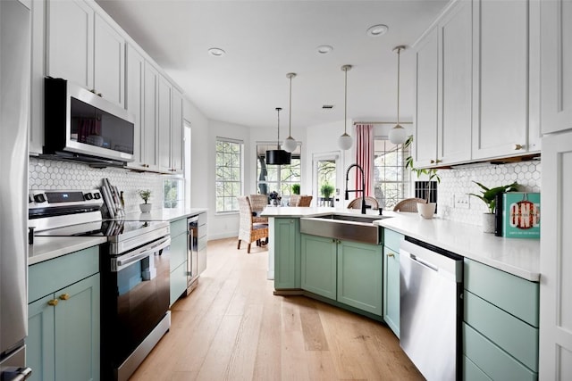 102 Hurst Creek Rd, Lakeway, TX 78734 - kitchen featuring appliances with stainless steel finishes, green cabinetry, a sink, a peninsula, and light countertops