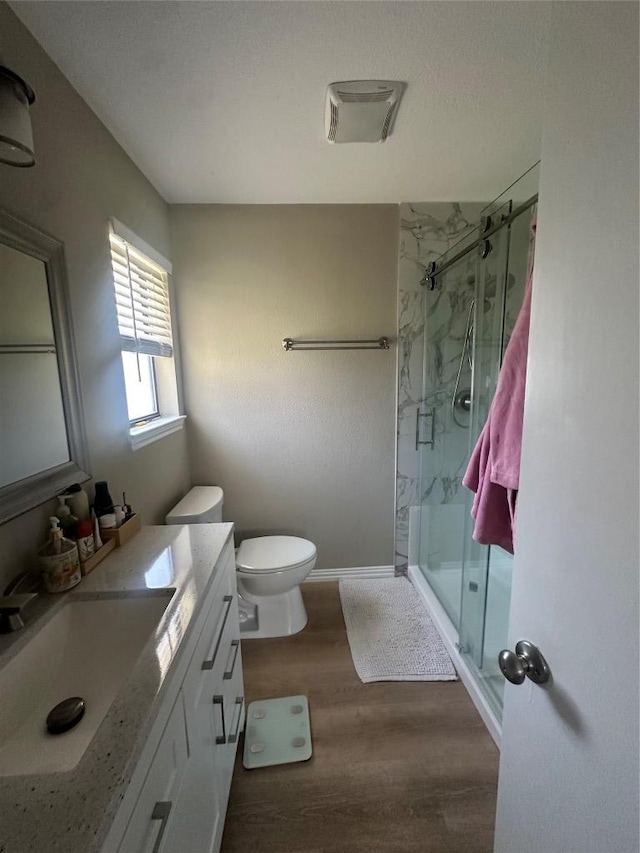 full bathroom featuring wood finished floors, a stall shower, vanity, and toilet