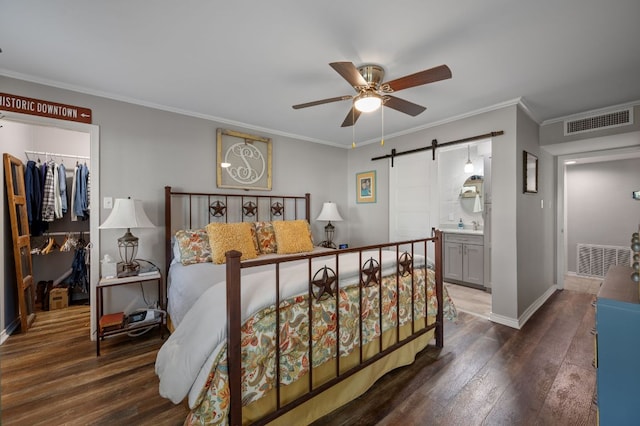 1135 Barton Hills Dr Unit 136, Austin, TX 78704 - bedroom with a barn door, a spacious closet, hardwood / wood-style flooring, a closet, and crown molding