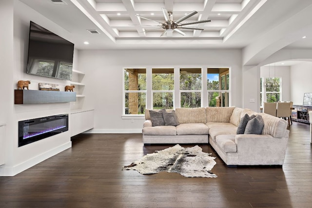 25101 Fawn Dr, Leander, TX 78641 - living room featuring arched walkways, coffered ceiling, a glass covered fireplace, dark wood-type flooring, and beam ceiling