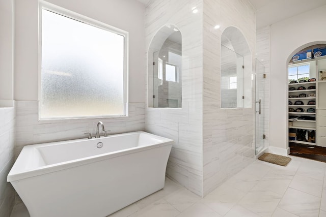 25101 Fawn Dr, Leander, TX 78641 - bathroom with plenty of natural light, tile walls, marble finish flooring, a freestanding tub, and a shower stall