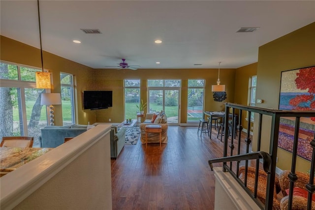 living room featuring a wealth of natural light, dark wood-style floors, ceiling fan, and visible vents