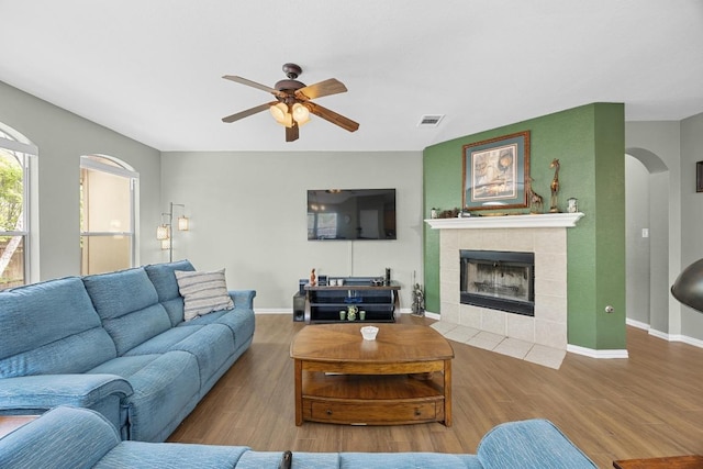2312 Mcgregor Ln, Cedar Park, TX 78613 - living area with a ceiling fan, arched walkways, wood finished floors, a tiled fireplace, and baseboards