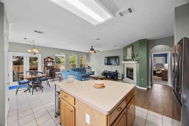 2312 Mcgregor Ln, Cedar Park, TX 78613 - kitchen featuring stainless steel fridge, a fireplace, light tile patterned floors, light countertops, and a center island