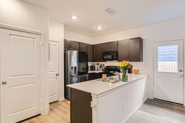 344 The Bad Way, Jarrell, TX 76537 - kitchen featuring black appliances, dark brown cabinets, a sink, light wood finished floors, and light countertops