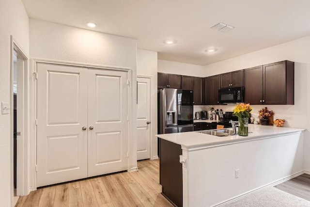 344 The Bad Way, Jarrell, TX 76537 - kitchen featuring black microwave, stainless steel refrigerator with ice dispenser, dark brown cabinets, a peninsula, and light wood-style flooring