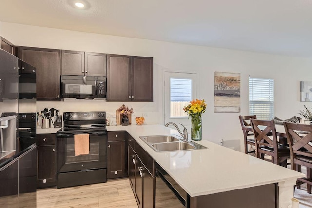 344 The Bad Way, Jarrell, TX 76537 - kitchen featuring black appliances, a sink, a peninsula, light countertops, and healthy amount of natural light