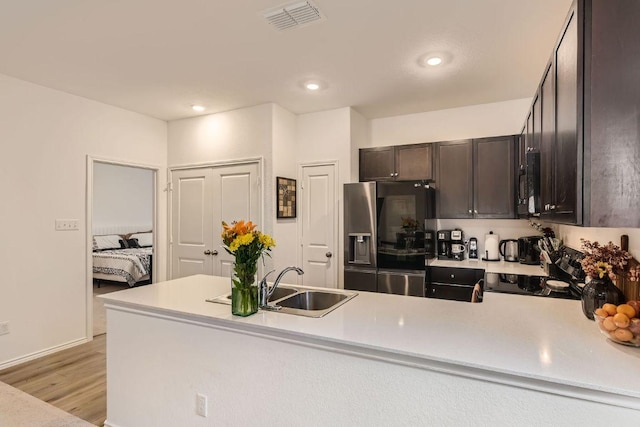 344 The Bad Way, Jarrell, TX 76537 - kitchen featuring stainless steel fridge with ice dispenser, stove, black microwave, light countertops, and dark brown cabinets