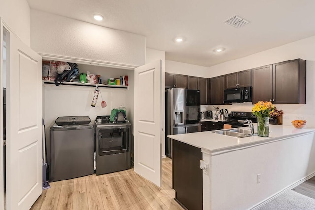 344 The Bad Way, Jarrell, TX 76537 - kitchen featuring black appliances, separate washer and dryer, a sink, dark brown cabinets, and light wood-style flooring