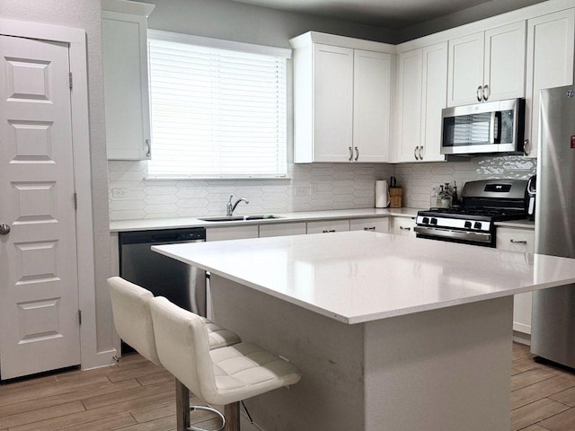 131 Harvest Ridge Blvd, Elgin, TX 78621 - kitchen with appliances with stainless steel finishes, light wood-style flooring, a breakfast bar, and decorative backsplash