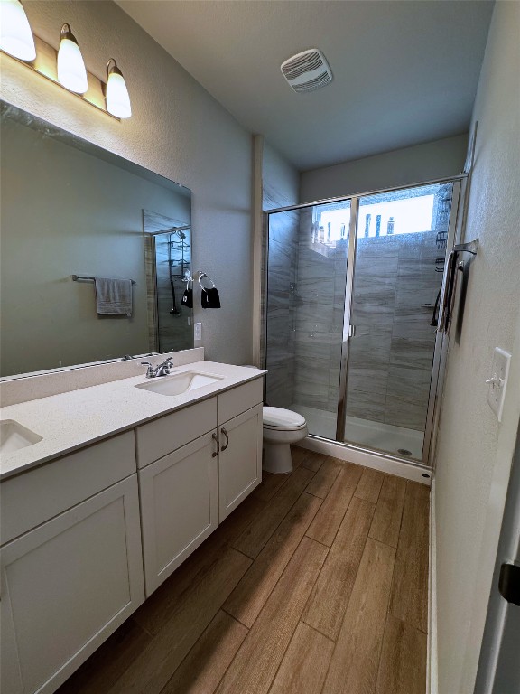 131 Harvest Ridge Blvd, Elgin, TX 78621 - full bathroom featuring wood finished floors, double vanity, a stall shower, and a textured wall