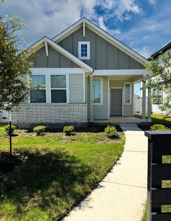 131 Harvest Ridge Blvd, Elgin, TX 78621 - view of front facade featuring board and batten siding, covered porch, and a front lawn