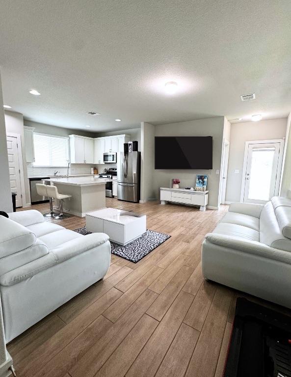 131 Harvest Ridge Blvd, Elgin, TX 78621 - living area featuring light wood finished floors, a textured ceiling, and recessed lighting