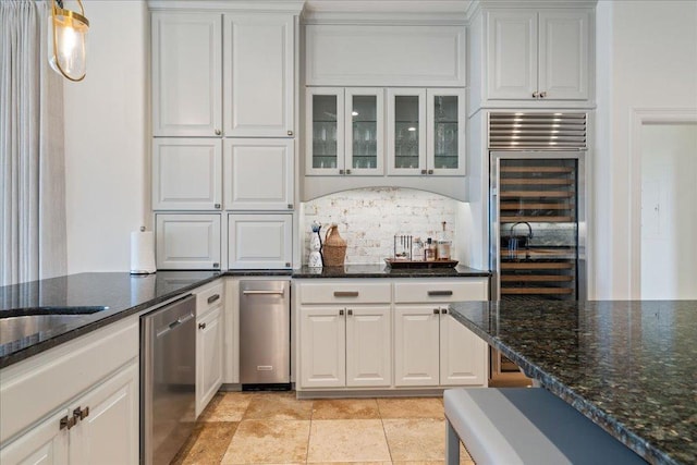 24729 Travis Lakeside Cv, Spicewood, TX 78669 - kitchen with stainless steel dishwasher, decorative backsplash, white cabinets, dark stone counters, and glass insert cabinets