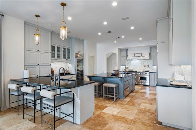 24729 Travis Lakeside Cv, Spicewood, TX 78669 - kitchen featuring premium appliances, a sink, a kitchen bar, decorative backsplash, and recessed lighting