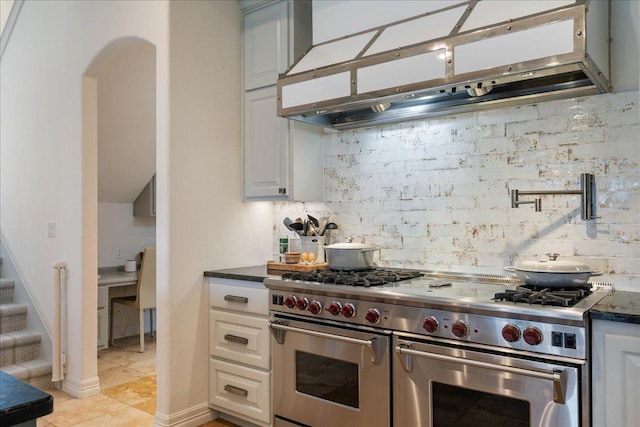 24729 Travis Lakeside Cv, Spicewood, TX 78669 - kitchen featuring double oven range, under cabinet range hood, tasteful backsplash, light tile patterned floors, and arched walkways
