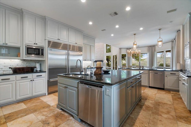 24729 Travis Lakeside Cv, Spicewood, TX 78669 - kitchen with built in appliances, gray cabinetry, decorative backsplash, an island with sink, and recessed lighting