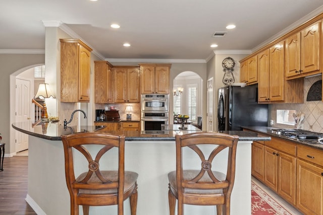 2907 Briona Wood Ln, Cedar Park, TX 78613 - kitchen with arched walkways, appliances with stainless steel finishes, dark countertops, recessed lighting, and a peninsula