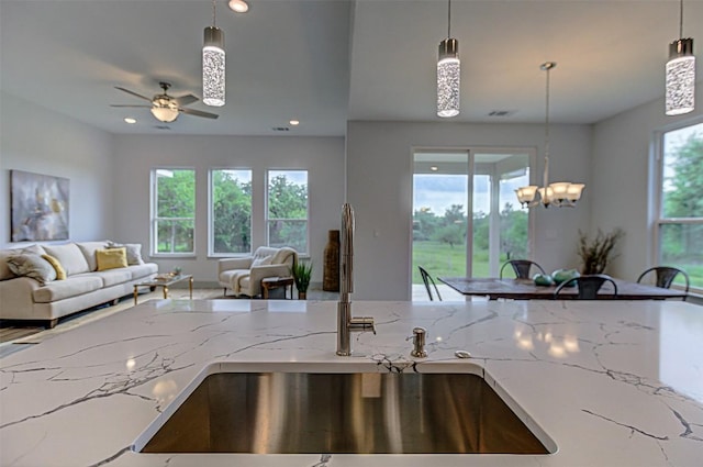 162 Puu Waa Waa Ln, Bastrop, TX 78602 - kitchen with open floor plan, a sink, light stone counters, ceiling fan, and hanging light fixtures