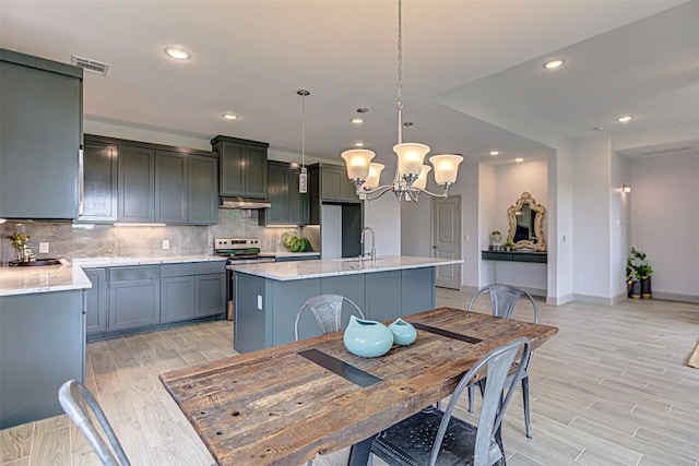 162 Puu Waa Waa Ln, Bastrop, TX 78602 - kitchen with electric range, under cabinet range hood, recessed lighting, a chandelier, and tasteful backsplash