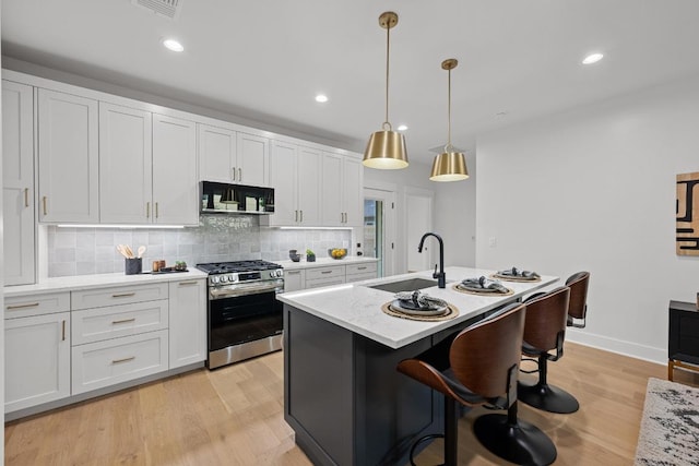 1906 Willow St Unit 2, Austin, TX 78702 - kitchen with gas range, black microwave, tasteful backsplash, white cabinets, and light wood-style floors