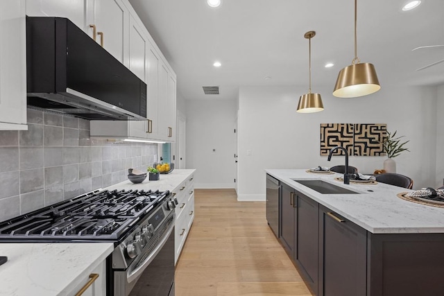 1906 Willow St Unit 2, Austin, TX 78702 - kitchen featuring appliances with stainless steel finishes, exhaust hood, white cabinets, tasteful backsplash, and light wood-style floors