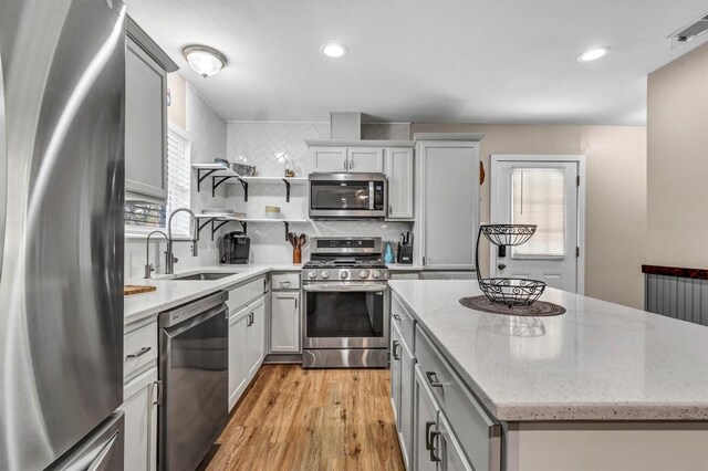 1701 Davis St, Taylor, TX 76574 - kitchen with appliances with stainless steel finishes, a center island, light wood finished floors, backsplash, and open shelves