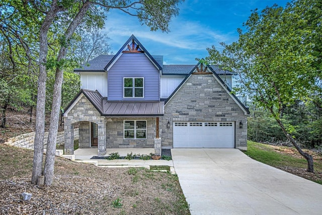view of front of property featuring stone siding, a garage, concrete driveway, a standing seam roof, and covered porch