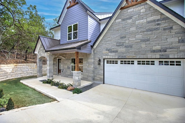 153 E Keanahalululu Ln, Bastrop, TX 78602 - view of front of home featuring stone siding, concrete driveway, a porch, a garage, and a metal roof