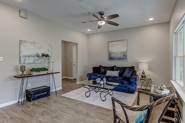 living room featuring a ceiling fan, baseboards, and wood finished floors