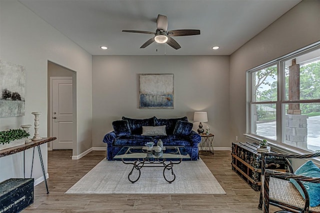 living area featuring baseboards, a ceiling fan, and wood finished floors