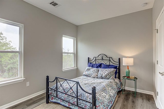 bedroom featuring visible vents, baseboards, and wood finished floors