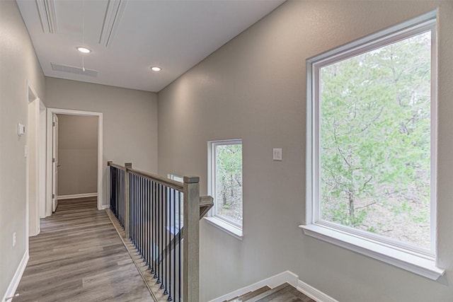hallway featuring baseboards, an upstairs landing, wood finished floors, and attic access