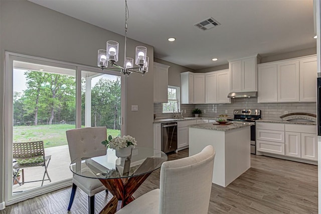 kitchen with appliances with stainless steel finishes, an inviting chandelier, backsplash, under cabinet range hood, and visible vents