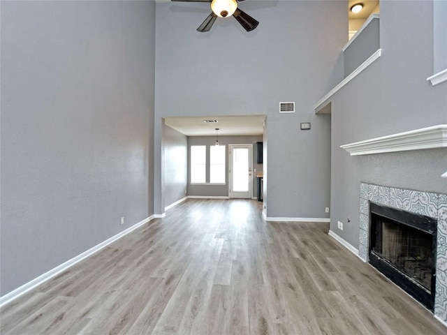 118 Dogwood Dr, Georgetown, TX 78626 - unfurnished living room with visible vents, baseboards, wood finished floors, a tiled fireplace, and a ceiling fan