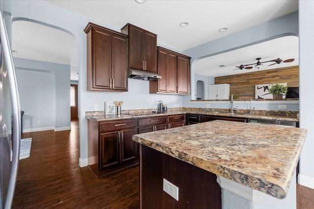 100 Matthews, Kyle, TX 78640 - kitchen with under cabinet range hood, stainless steel refrigerator, dark brown cabinets, arched walkways, and ceiling fan