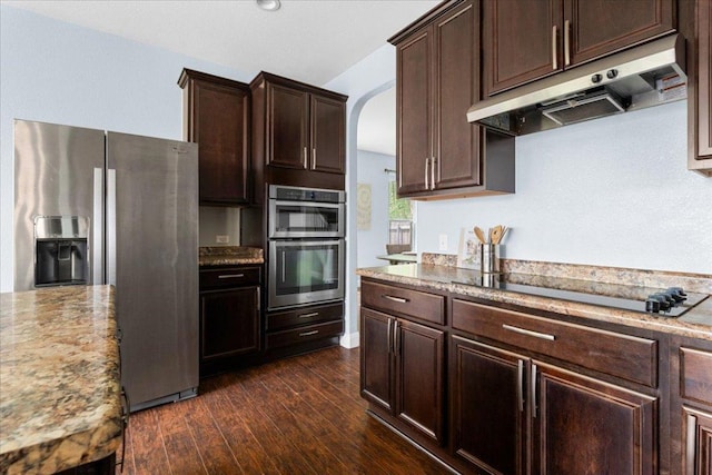 100 Matthews, Kyle, TX 78640 - kitchen featuring appliances with stainless steel finishes, under cabinet range hood, dark brown cabinets, arched walkways, and dark wood-type flooring
