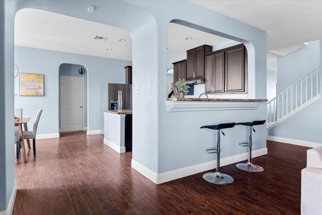 100 Matthews, Kyle, TX 78640 - kitchen with arched walkways, stainless steel refrigerator with ice dispenser, dark brown cabinets, dark wood-style flooring, and baseboards