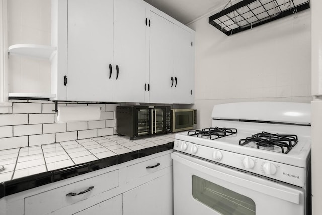 7202 Marcell St, Austin, TX 78752 - kitchen with white range with gas stovetop, tile counters, white cabinets, and tasteful backsplash
