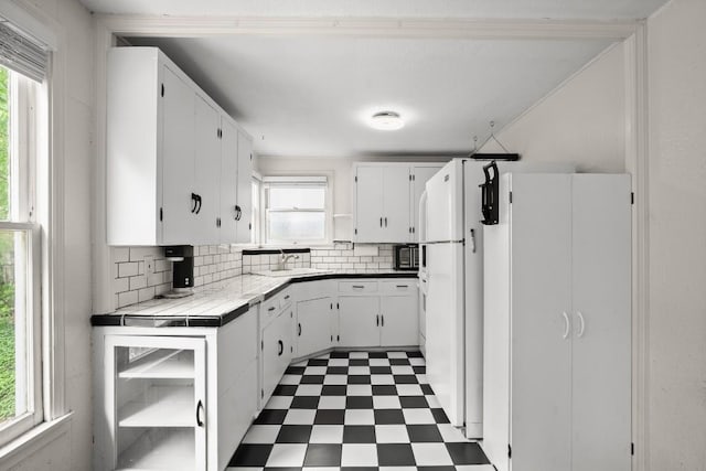 7202 Marcell St, Austin, TX 78752 - kitchen featuring tile patterned floors, healthy amount of natural light, tasteful backsplash, and white cabinets