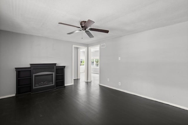 7202 Marcell St, Austin, TX 78752 - unfurnished living room with dark wood-style floors, a glass covered fireplace, a ceiling fan, and a textured ceiling