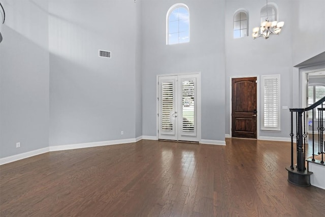 foyer featuring an inviting chandelier, stairway, dark wood-style flooring, visible vents, and baseboards