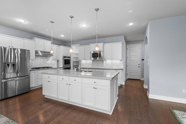 kitchen featuring white cabinets, appliances with stainless steel finishes, under cabinet range hood, and decorative backsplash