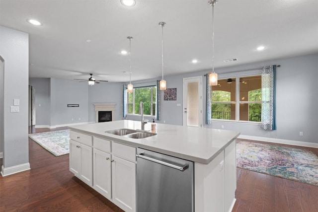 2015 Colina Cv, Cedar Park, TX 78613 - kitchen featuring stainless steel dishwasher, open floor plan, ceiling fan, a fireplace, and white cabinetry