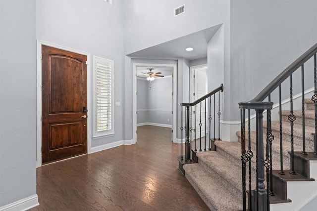 foyer entrance featuring visible vents, wood finished floors, a ceiling fan, and stairway